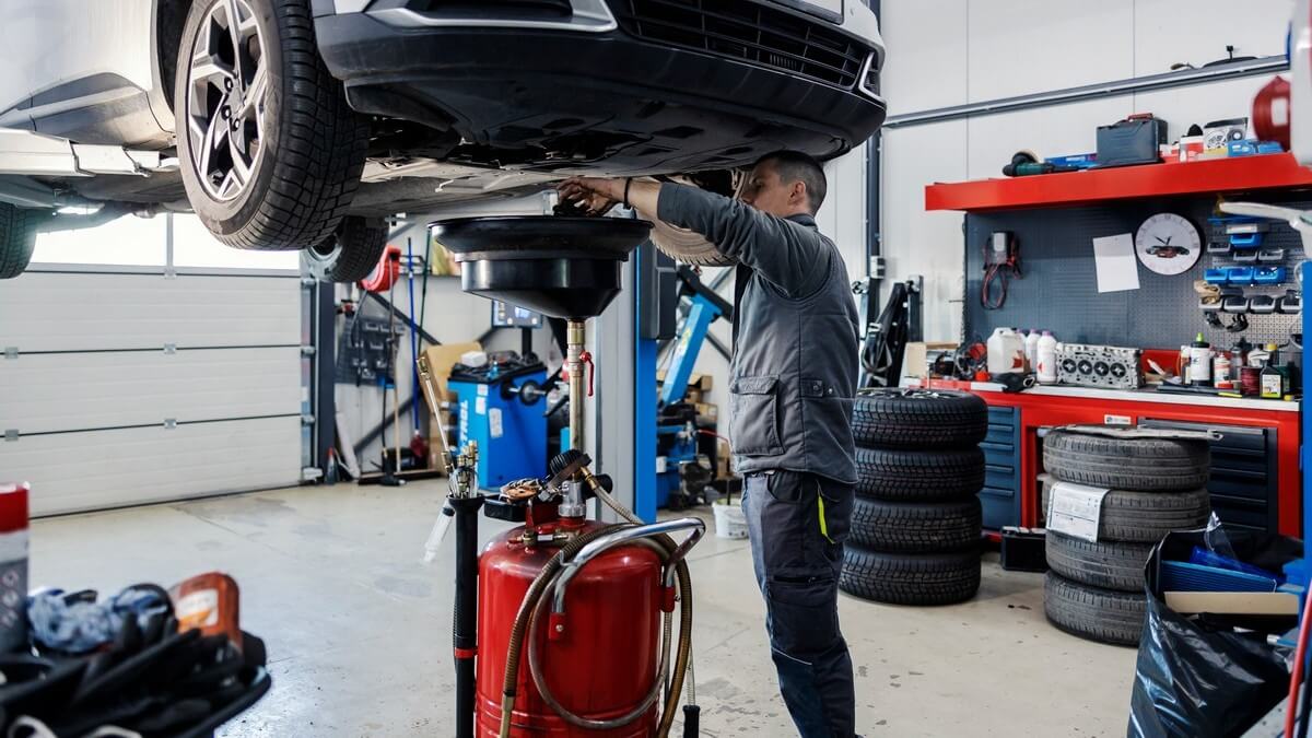 Vidange d'huile moteur sous une voiture soulevée dans l'atelier